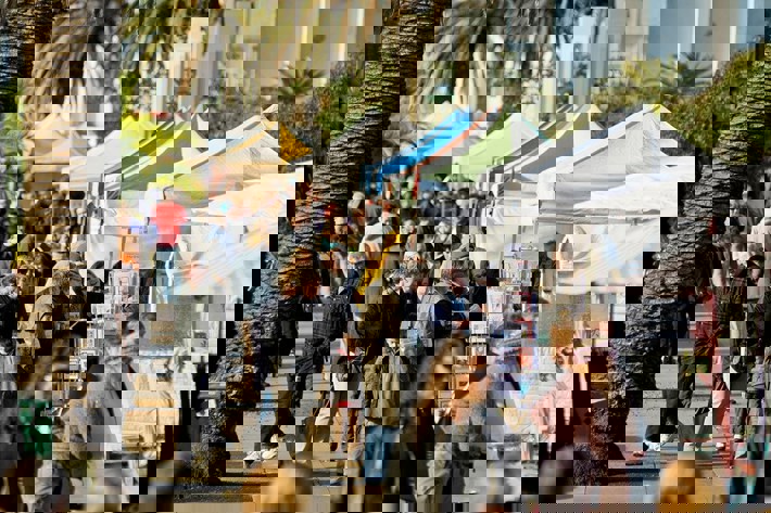 Crowds browsing and walking past stalls at the St Kilda Esplanade Market