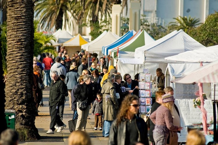 Crowds browsing and walking past stalls at the St Kilda Esplanade Market